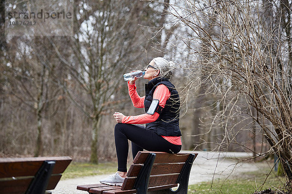 Reife Frau trainiert im Park  trinkt Flaschenwasser