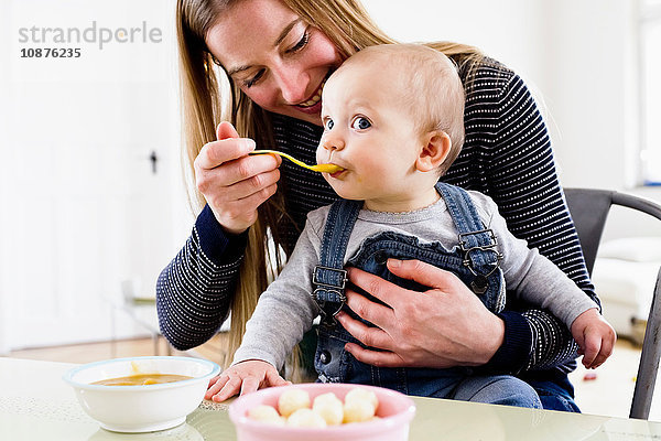 Frau füttert Baby-Tochter bei Tisch