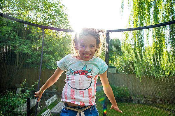 Mädchen hüpft auf Gartentrampolin