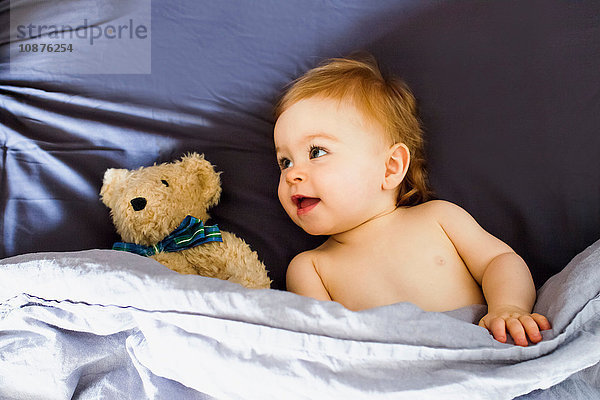 Im Bett liegendes Mädchen mit Teddybär