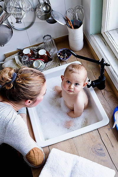 Portrait eines in der Küchenspüle badenden kleinen Jungen