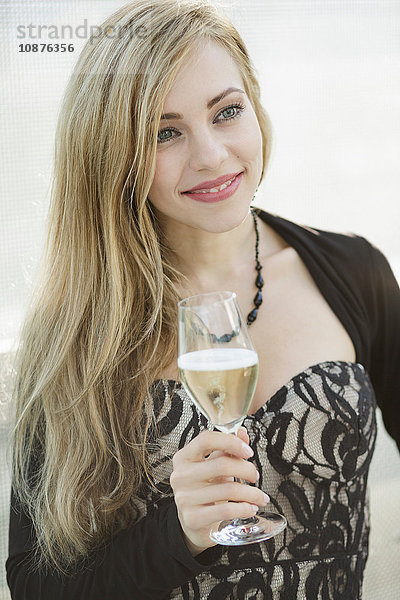 Langhaarige blonde kultivierte junge Frau trinkt Champagner