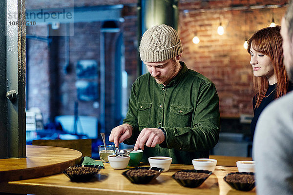 Coffee-Shop-Team bereitet Schalen mit Kaffee und Kaffeebohnen für die Verkostung vor