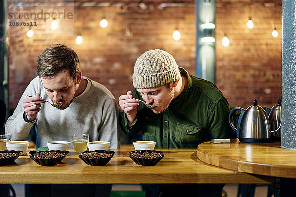 Coffee-Shop-Team schlürft Schalen mit Kaffee und Kaffeebohnen bei der Verkostung