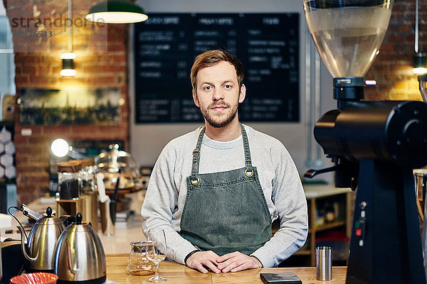 Porträt eines jungen männlichen Barista an der Kaffeehaus-Küchentheke