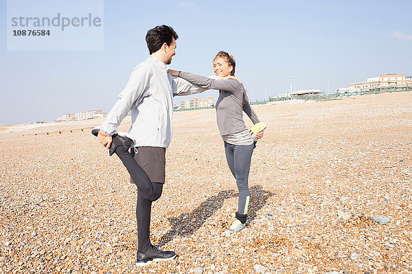Mann und Frau trainieren  auf einem Bein stehend am Strand von Brighton