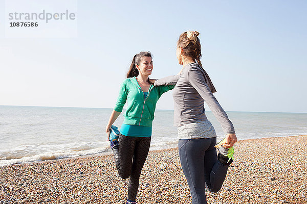 Zwei Frauen trainieren  auf einem Bein stehend am Strand von Brighton