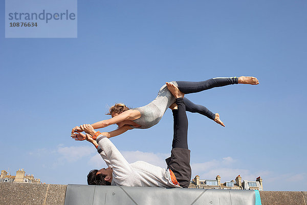 Mann und Frau praktizieren akrobatisches Yoga an der Wand