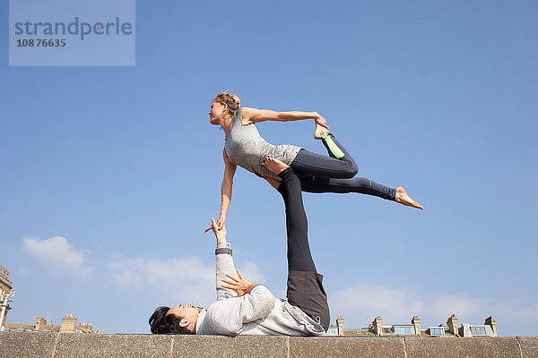 Mann und Frau praktizieren akrobatisches Yoga an der Wand