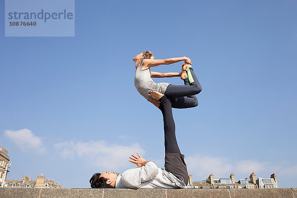 Mann und Frau üben akrobatische Yoga-Balance an der Wand