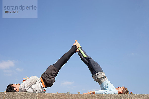 Mann und Frau praktizieren akrobatisches Yoga vor blauem Himmel