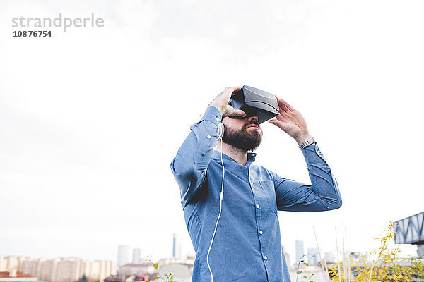 Junger männlicher Designer testet Virtual-Reality-Headset auf Büro-Dachterrasse