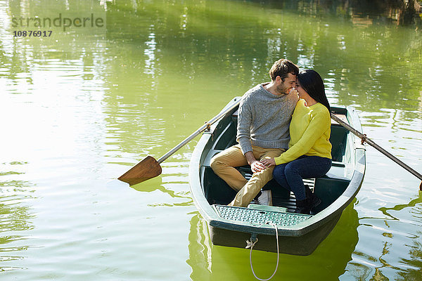Paar im Ruderboot auf dem See Kopf an Kopf umarmend