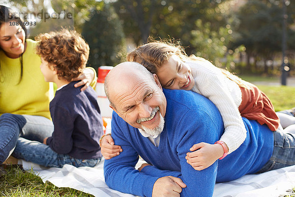 Mädchen im Park liegt lächelnd auf Großvater
