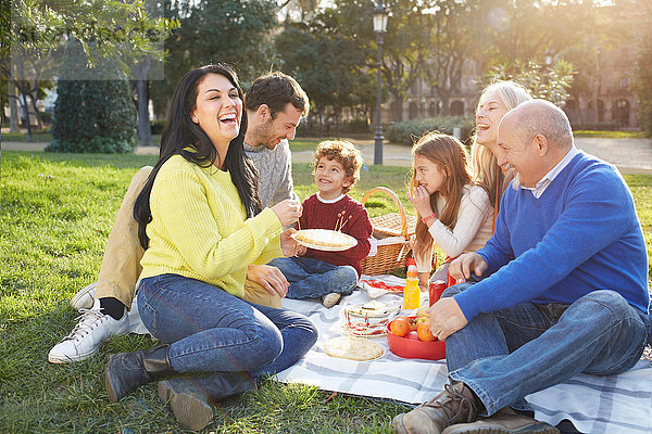 Mehrgenerationen-Familie sitzt auf Gras und macht Picknick