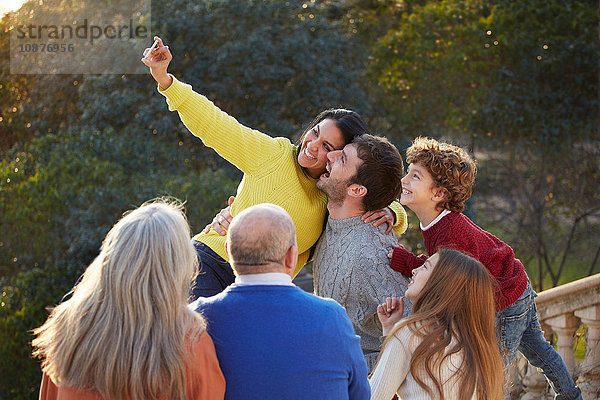 Mittelgroße erwachsene Frau und Familie nutzen Smartphone  um sich selbst in den Park zu bringen