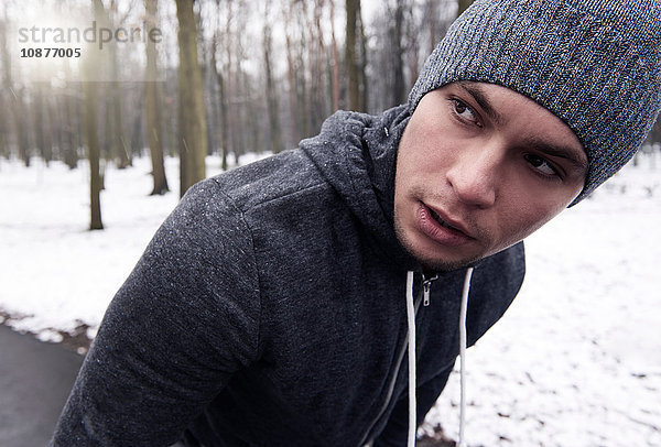 Junger Mann trainiert in verschneitem Wald  schaut weg