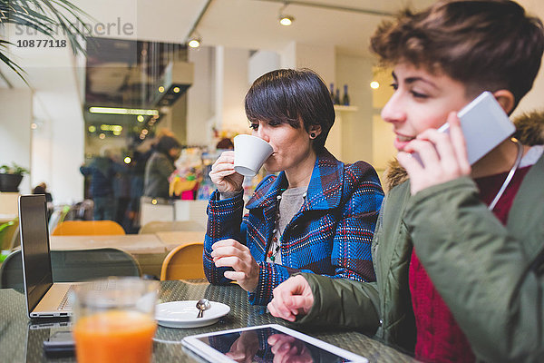 Zwei Schwestern im Cafe mit Laptop  digitalem Tablet und Smartphone