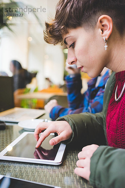 Junge Frau im Café  die ein digitales Tablett benutzt