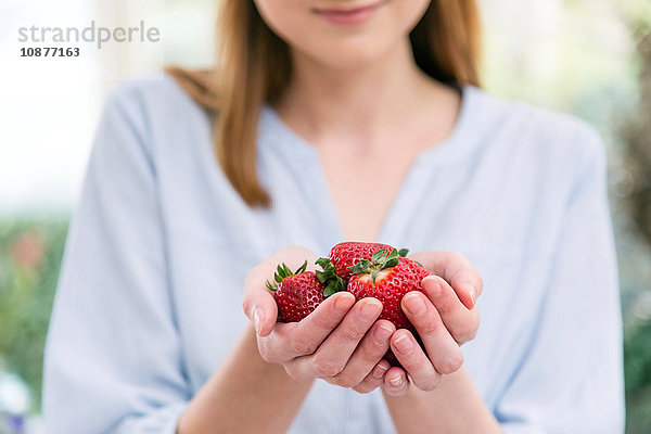 Frau mit schalenförmigen Händen  die Erdbeeren halten