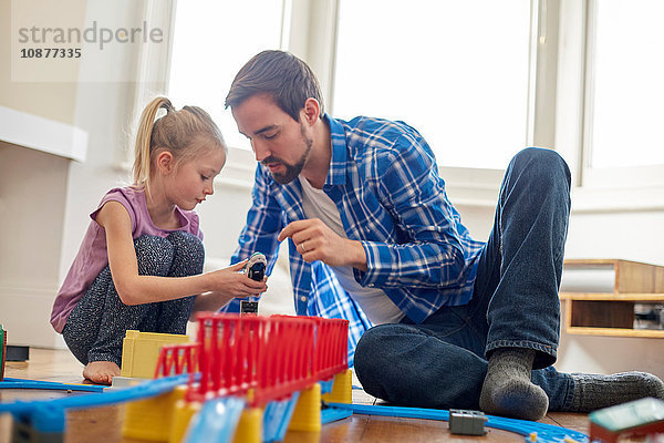 Vater und Tochter spielen mit einer Spielzeugeisenbahn