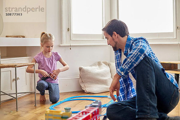 Vater und Tochter spielen mit einer Spielzeugeisenbahn