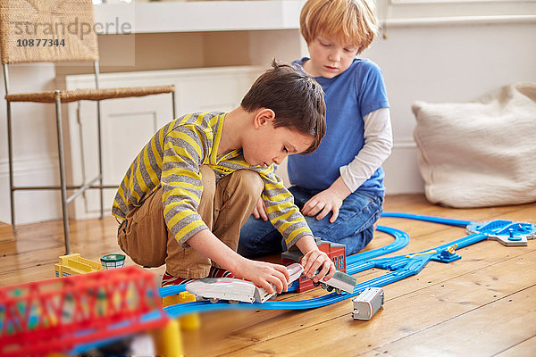 Zwei kleine Jungen spielen mit einer Spielzeugeisenbahn