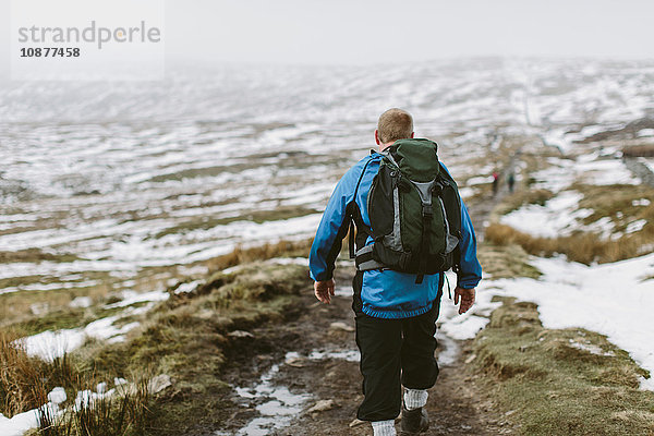 Wanderer durchquert schneebedecktes Moor  Yorkshire Dales National Park  England