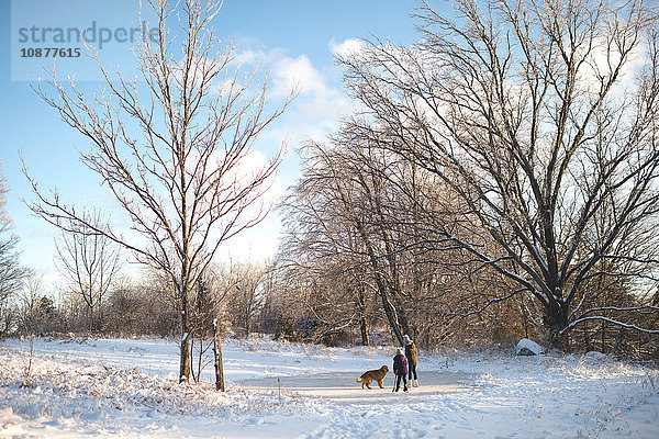 Zwei junge Mädchen mit Hund in verschneiter Landschaft