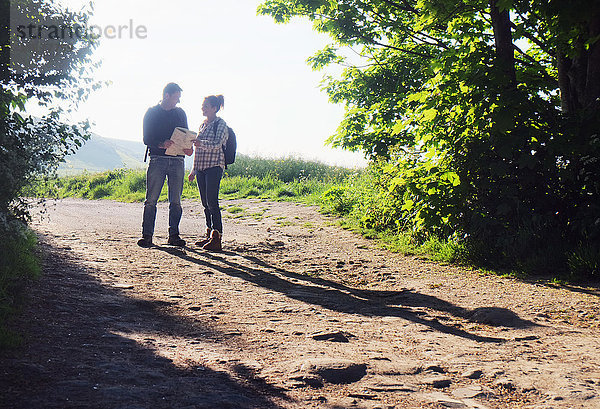 Paar wandert auf Feldwegen und liest Karte