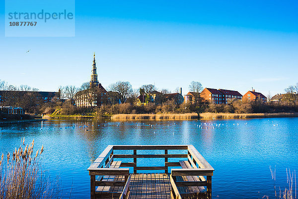 Blick auf den hölzernen Pier am Fluss und die entfernte Kirchturmspitze  Kopenhagen  Dänemark