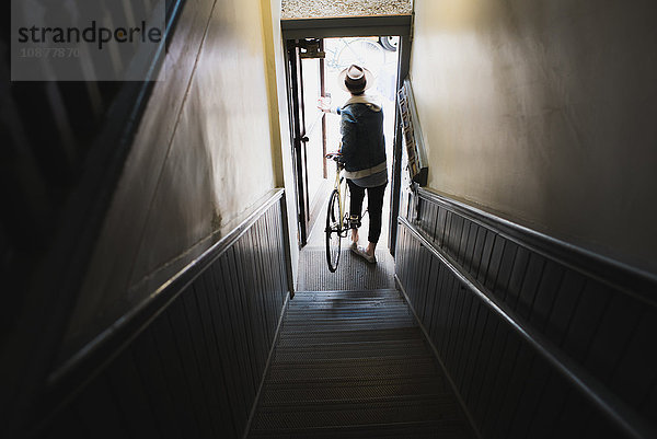 Junger Mann unten an der Treppe  Verlassen des Gebäudes mit Fahrrad  erhöhte Ansicht