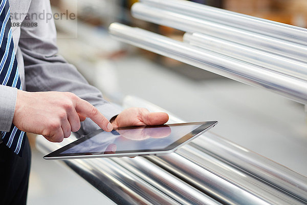 Nahaufnahme der Inventur der Arbeiter bei der Entnahme von Metallstäben mittels digitalem Tablett-Touchscreen in einer Rollladenfabrik