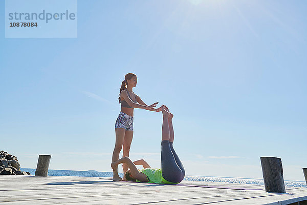 Frauen auf dem Pier  die sich gegenseitig die Knöchel halten und trainieren