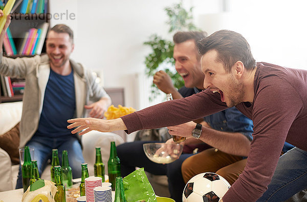Gruppe von Männern sieht Sportereignis im Fernsehen und feiert Fussball