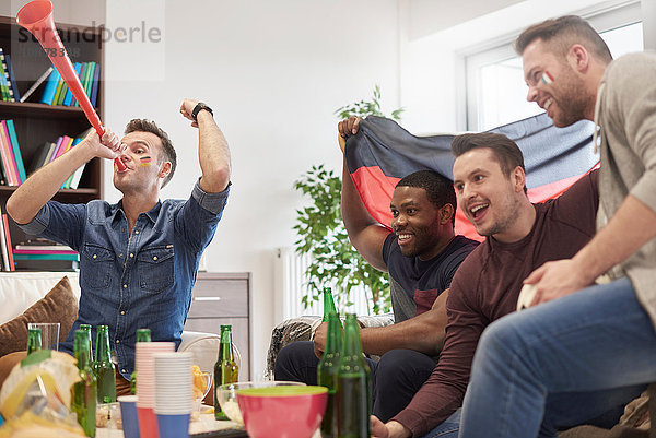 Gruppe von Männern  die im Fernsehen ein Sportereignis mit deutscher Flagge verfolgen und feiern