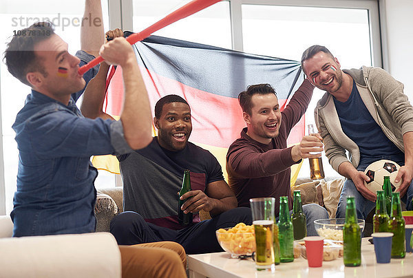 Gruppe von Männern  die mit deutscher Flagge und Fußball im Fernsehen ein Sportereignis verfolgen und feiern