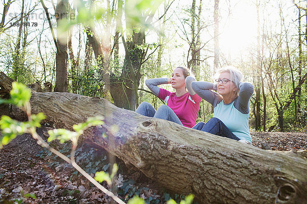 Frauen im Wald Hände hinter dem Kopf  die sich gegen einen umgefallenen Baum setzen