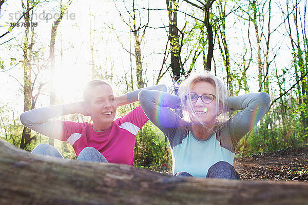 Frauen im Wald Hände hinter dem Kopf  die sich gegen einen umgefallenen Baum setzen