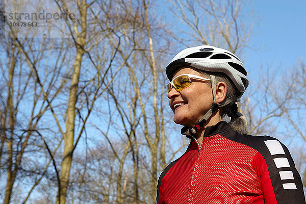 Niedriger Blickwinkel auf eine Frau mit Fahrradhelm und Sonnenbrille  die lächelnd wegschaut