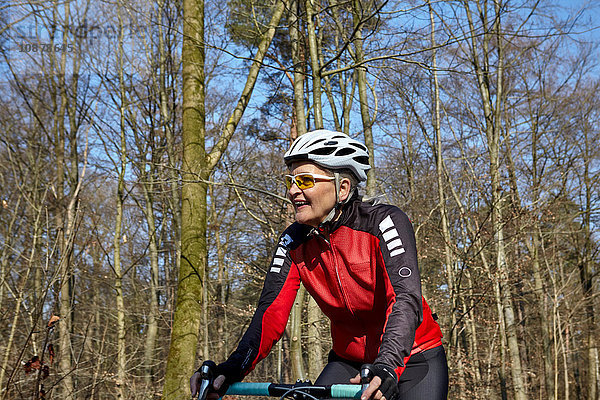 Frau mit Fahrradhelm und Sonnenbrille fährt Rad und schaut lächelnd weg