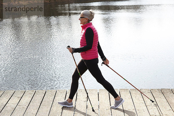 Seitenansicht der Nordic-Walking-Frau am Teich in voller Länge