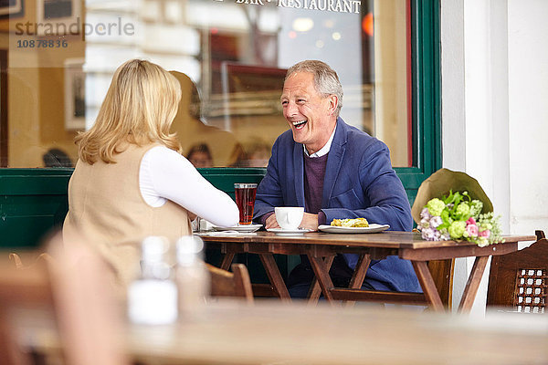 Reifes Paar beim Date lacht gemeinsam am Tisch im Straßencafé