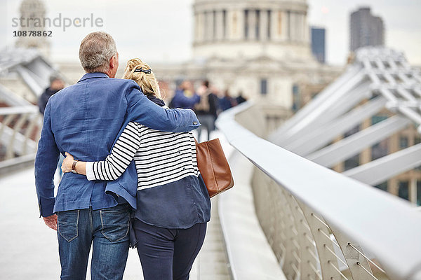 Rückansicht eines reifen Liebespaares beim Überqueren der Millennium Bridge  London  UK