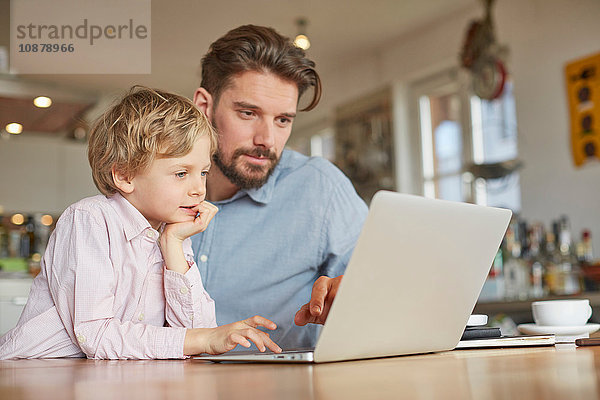 Vater und Sohn benutzen Laptop im Heimbüro