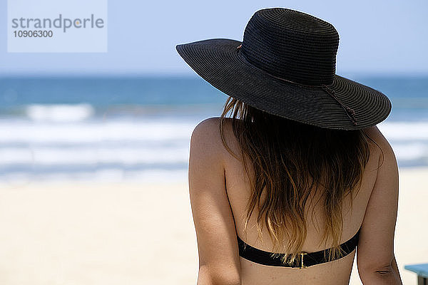 Back view of female teenager with hat at the beach
