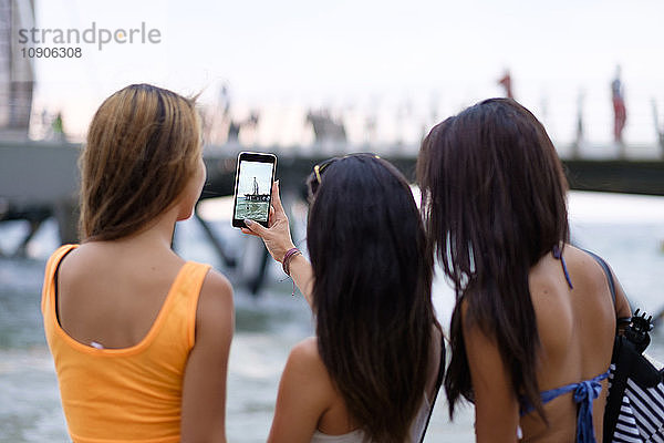 Mexico  Puerto Vallarta  three young women taking a smartphone photo of Los Muertos pier