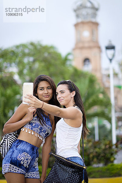 Mexico  Puerto Vallarta  two young women taking a smartphone selfie in the city