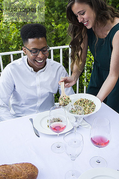 Woman serving tabbouleh to her guest during a summer dinner