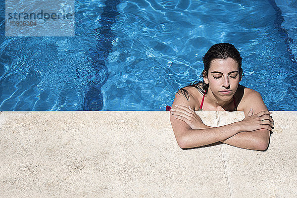 Portrait of a woman with closed eyes in a swimming pool relaxing at the edge